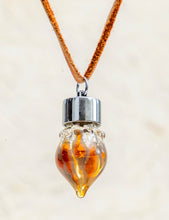 A glass pendant necklace filled with natural perfume oil, similar to what guests receive when booking Sol Aromatics' Halloween Potions of Intention experience